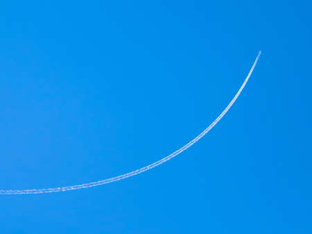 airplane contrail against clear blue sky with copy spaceの写真素材
