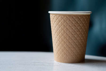 Take away a plastic cup of coffee on a wooden table with a blurred background with space for text or advertising.の写真素材