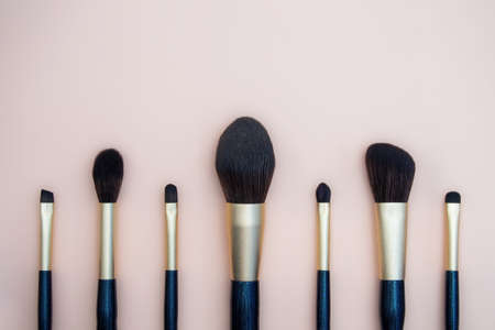 Assortment of female make-up of various face brushes. A set of professional dark blue and golden makeup brushes on a pink background. photoの写真素材