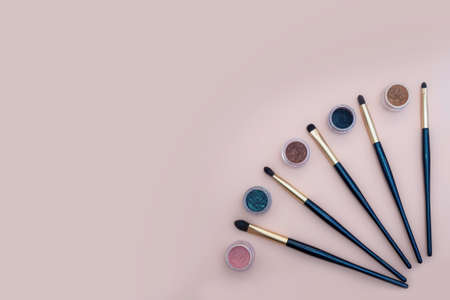 Composition with decorative makeup products golden brushes and colorful eye shadows on pastel pink background. photoの写真素材
