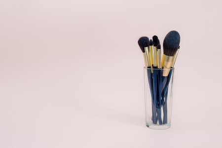 Assortment of female make-up of various face brushes. A set of professional dark blue and golden makeup brushes on a pink background. photoの写真素材