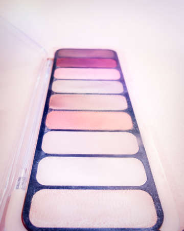 Composition with decorative makeup products golden brushes and colorful eye shadows on pastel pink background. photoの写真素材