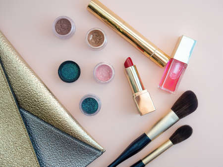 Top view of cosmetics standing out from golden makeup bag on pink background. photoの写真素材