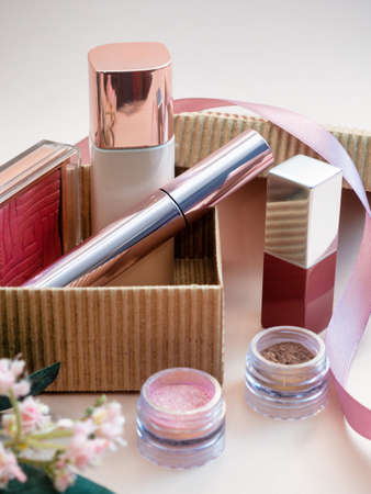 a set of cosmetics for a female face and eye makeup in a brown craft box on a pink background. photoの写真素材