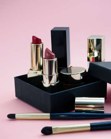 set of cosmetics for a female face and eye makeup in a black craft box on a pink background. photoの写真素材