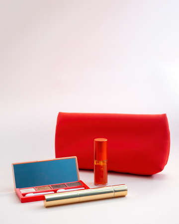 Top view of cosmetics standing out from red cosmetic bag on pink background. photoの写真素材