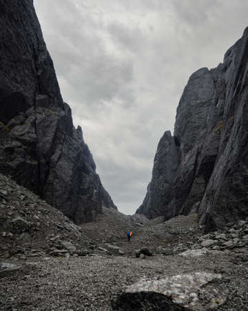 A young woman tourist with a backpack goes through a lifeless rocky pass. photoの写真素材