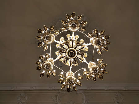 Luxurious interior chandelier has lit candles and a dark background. Noble candelabra hang from the ceiling. photoの写真素材