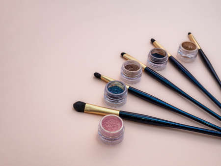 Composition with decorative makeup products golden brushes and colorful eye shadows on pastel pink background. photoの写真素材