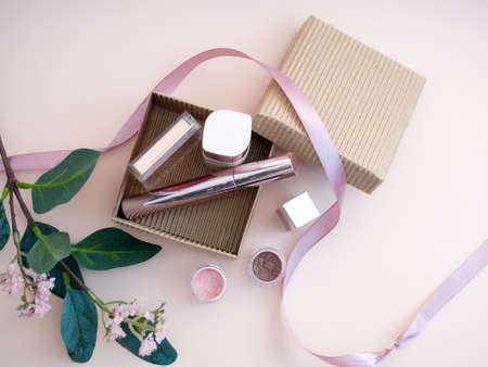 a set of cosmetics for a female face and eye makeup in a brown craft box on a pink background. photoの写真素材