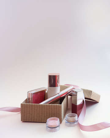 a set of cosmetics for a female face and eye makeup in a brown craft box on a pink background. photoの写真素材
