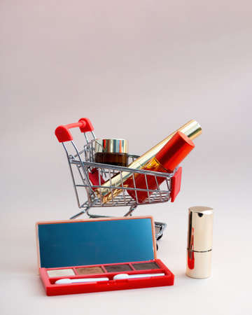 Front view of a shopping cart with makeup products on a pink background. Cosmetic shopping concept. photoの写真素材