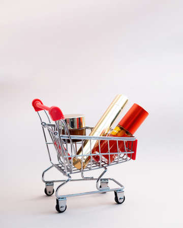 Front view of a shopping cart with makeup products on a pink background. Cosmetic shopping concept. photoの写真素材