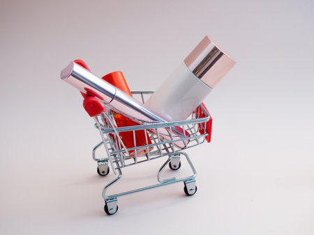 Front view of a shopping cart with makeup products on a pink background. Cosmetic shopping concept. photoの写真素材