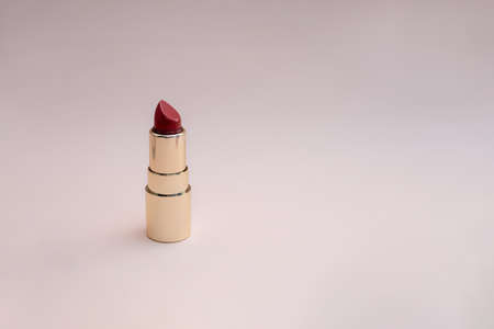red lipstick in a gold case on a pink background. photoの写真素材