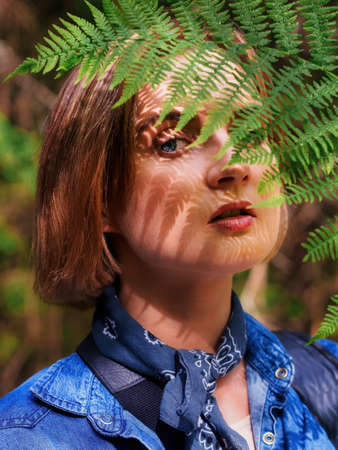 The young woman with fern leaf and shadow on face. nature concept. close up portrait. photoの写真素材