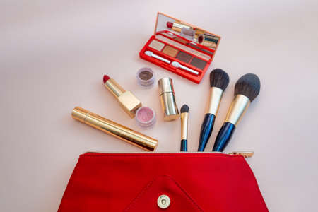 Top view of cosmetics standing out from red cosmetic bag on pink background. photoの写真素材