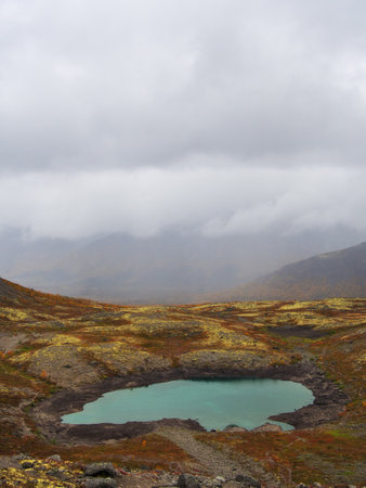 Lake with turquoise water in the mountains in autumn on a cloudy day. view from aboveの写真素材
