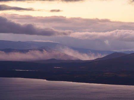 A beautiful mountain landscape with a lake in the distance and low creeping clouds. Autumn mountains of Khibiny in Russia. photoの写真素材