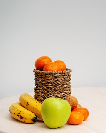 A variety of fruits and nuts on a wooden table. Tangerines in a wicker basket, bananas, apples and walnuts. photoの写真素材
