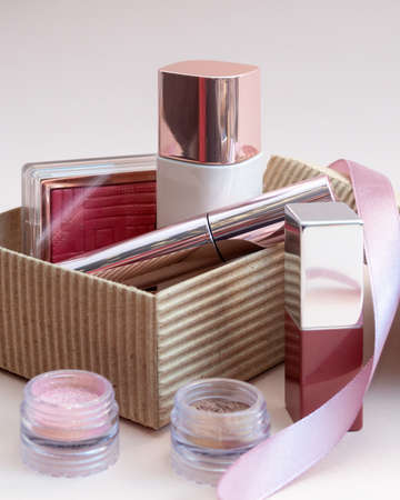 a set of cosmetics for a female face and eye makeup in a brown craft box on a pink background. photoの写真素材