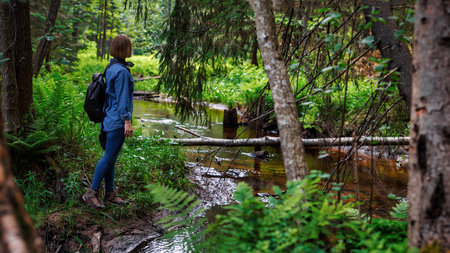 A woman explores new, magical and fantastic places around the world, surrounded by nature. A woman hiker crosses a forest stream. photoの写真素材