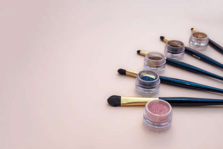 Composition with decorative makeup products golden brushes and colorful eye shadows on pastel pink background. photoの写真素材