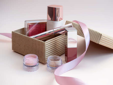 a set of cosmetics for a female face and eye makeup in a brown craft box on a pink background. photoの写真素材