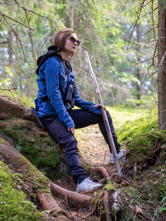 Hiking. Woman hiker in forest taking a rest sitting down. beautiful young caucasian model. photoの写真素材