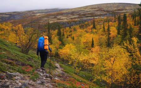 A young woman with a backpack and trekking poles in the Khibiny mountains. The concept of a healthy and active lifestyle. Girl on the background of nature mountains. photoの写真素材