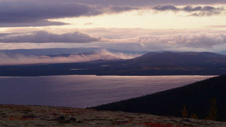 A beautiful mountain landscape with a lake in the distance and low creeping clouds. Autumn mountains of Khibiny in Russia. photoの写真素材