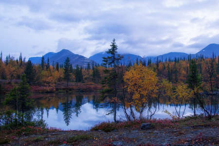 Reflection of mountains and clouds in the calm surface of the lake. Peaceful landscape. Khibiny