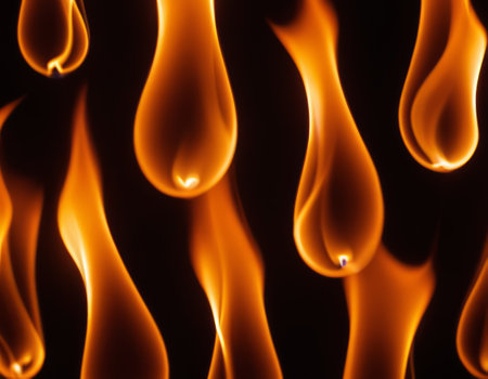 A close-up view of dynamic and intense flames in various shades of orange, yellow, and red, creating a contrast with the dark background and conveying a sense of heat and energyの素材