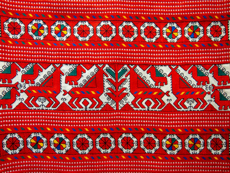 A beautifully crafted textile features vivid red and white patterns with animals and floral designs. This artistic piece reflects the rich cultural heritage and skilled handiwork of a local artisan.の写真素材