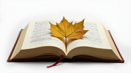 A vibrant autumn leaf is delicately placed on the open pages of a book, blending nature with literature. This cozy arrangement invites a moment of peaceful contemplation and nostalgia for the season.の素材