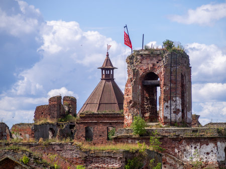 Remnants of ancient fortifications rise majestically, with a wooden tower topped by a flag. Greenery...