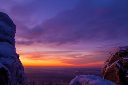Epic red sunset over the rocks and stones of Ural mountains covered with snowy pines