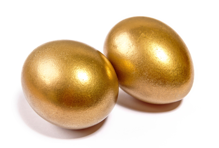 Two gilt Easter eggs lying on a white backgroundの写真素材