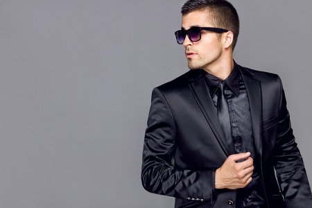Young handsome man in a black suit with a tie and glassesの写真素材