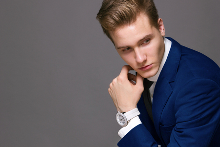 young man with a clock in blue jacketの写真素材