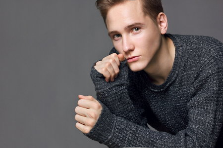 a young man in a gray sweater on a gray background studioの写真素材