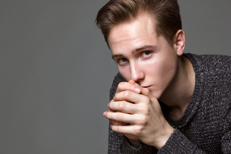a young man in a gray sweater on a gray background studioの写真素材