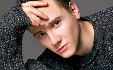 a young man in a gray sweater on a gray background studioの写真素材