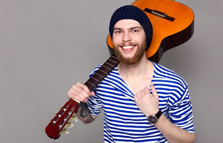 Portrait of a hipster in a striped shirt holding a guitarの写真素材