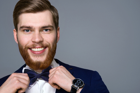 the bearded young man model smiling portrait on gray background, studioの写真素材
