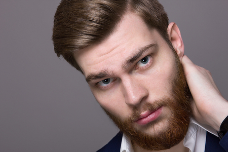 portrait of a young man with a big beard in the studio on a gray backgroundの写真素材