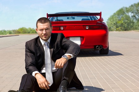handsome young businessman near his red carの写真素材