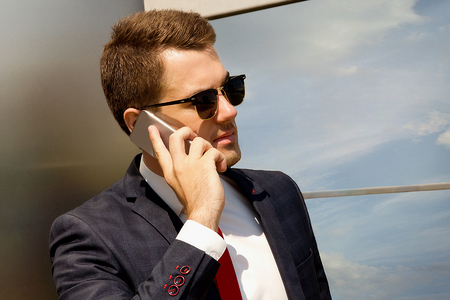 Handsome young man in fashion sunglasses calling on the phoneの写真素材
