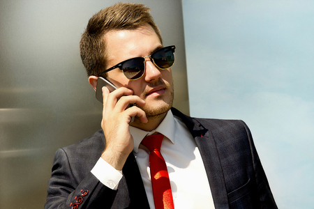 Handsome young man in fashion sunglasses calling on the phoneの写真素材