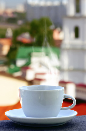 on the background of buildings on the balcony with a cup of tea, coffeeの写真素材
